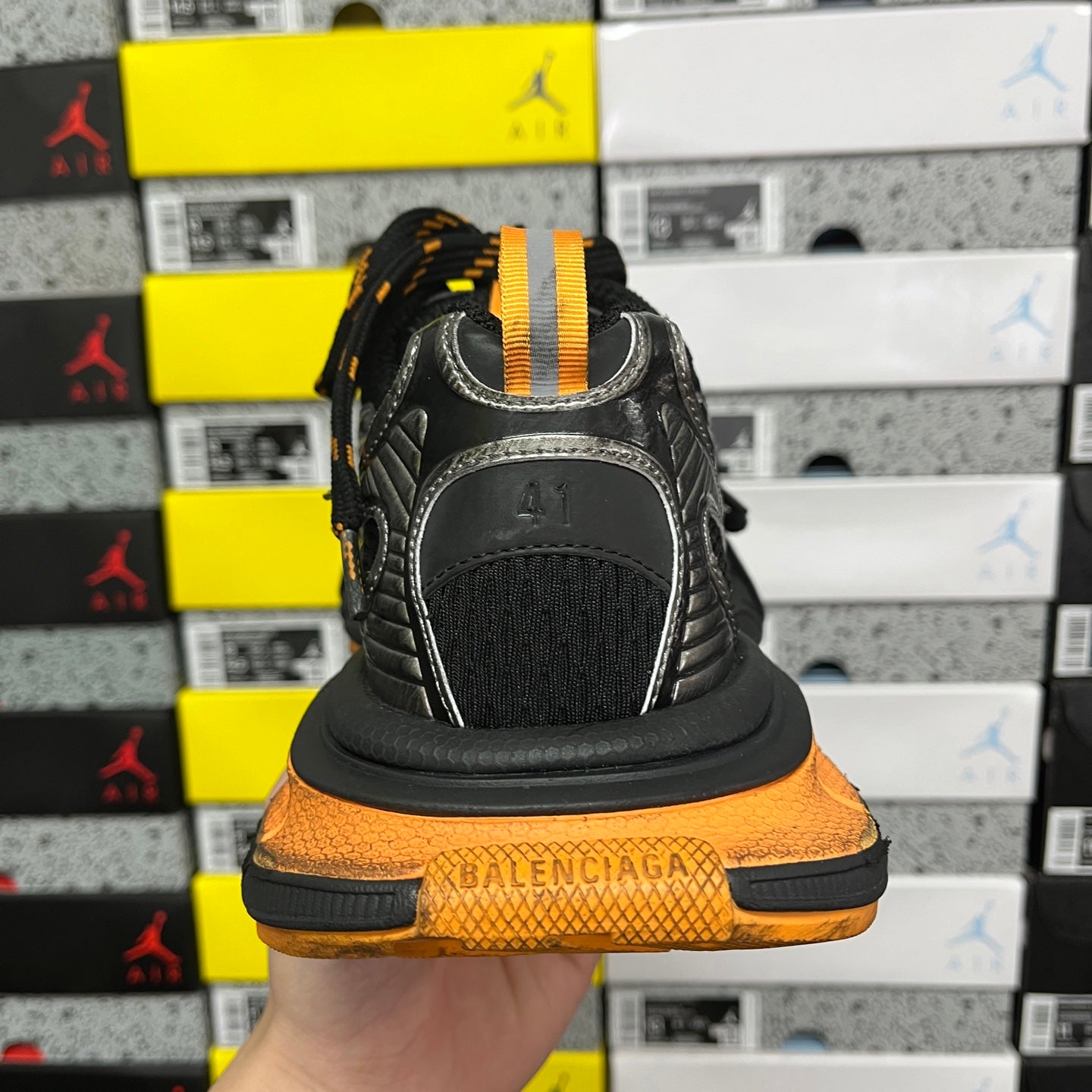 Black sneaker heel with orange midsole and stitched branding panel
