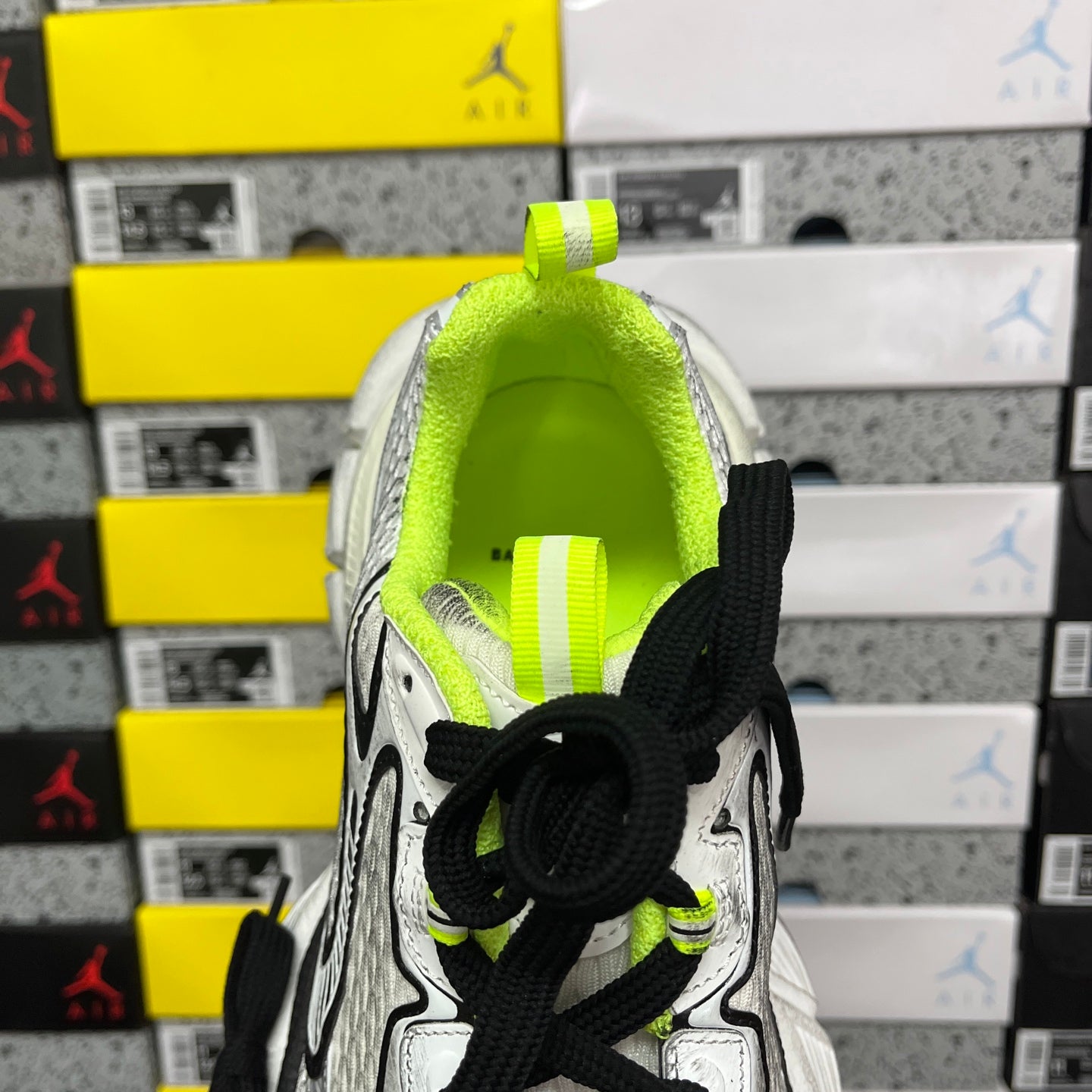 Silver running sneaker with neon green collar and black lace overlay