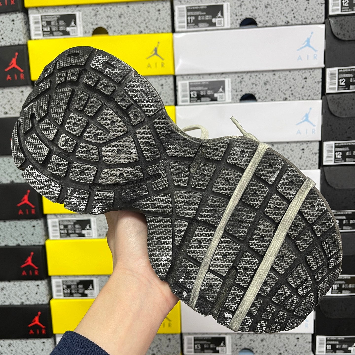 Outsole of light gray unisex sneakers with deep grid tread pattern