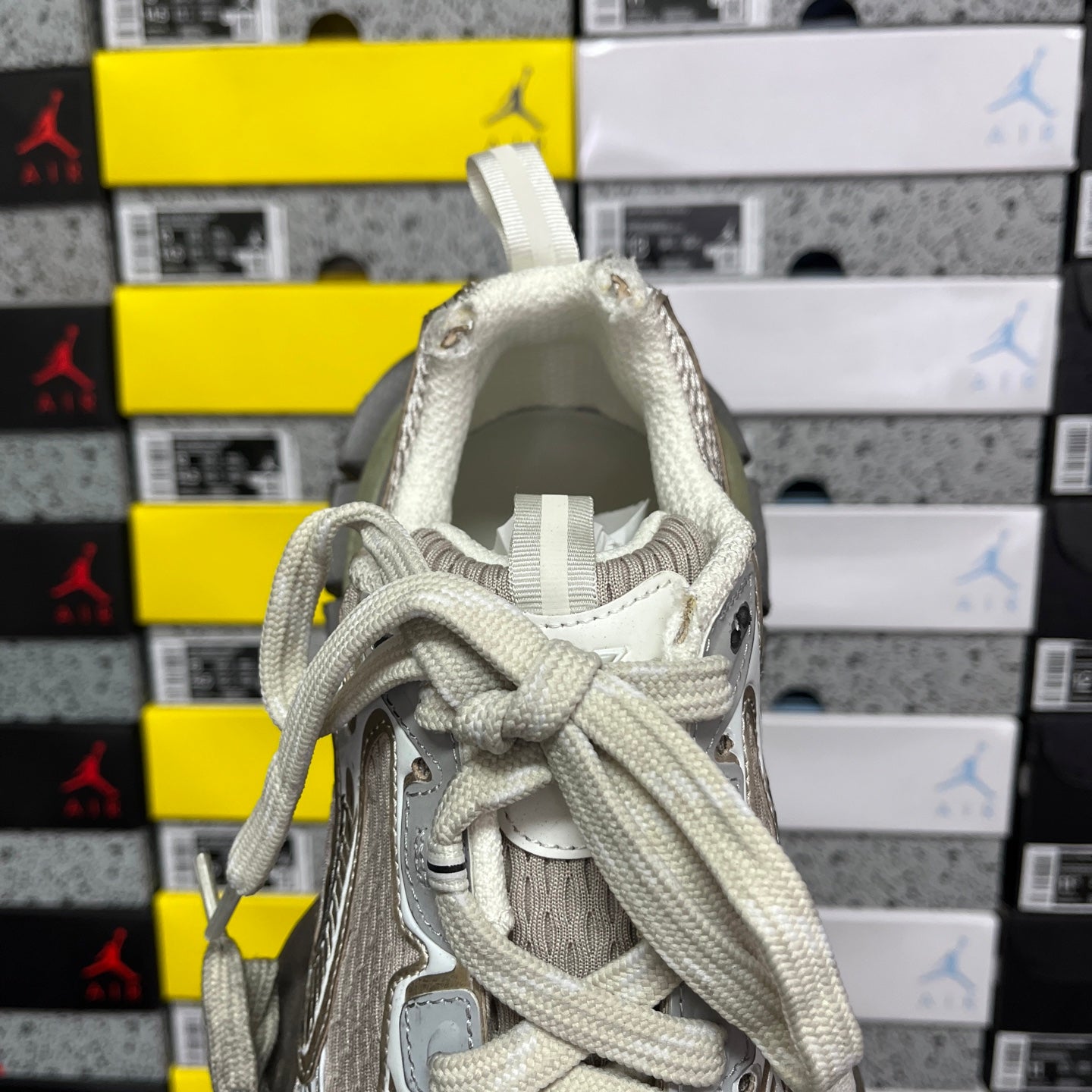 Open collar of light gray unisex sneakers with layered laces and padded interior