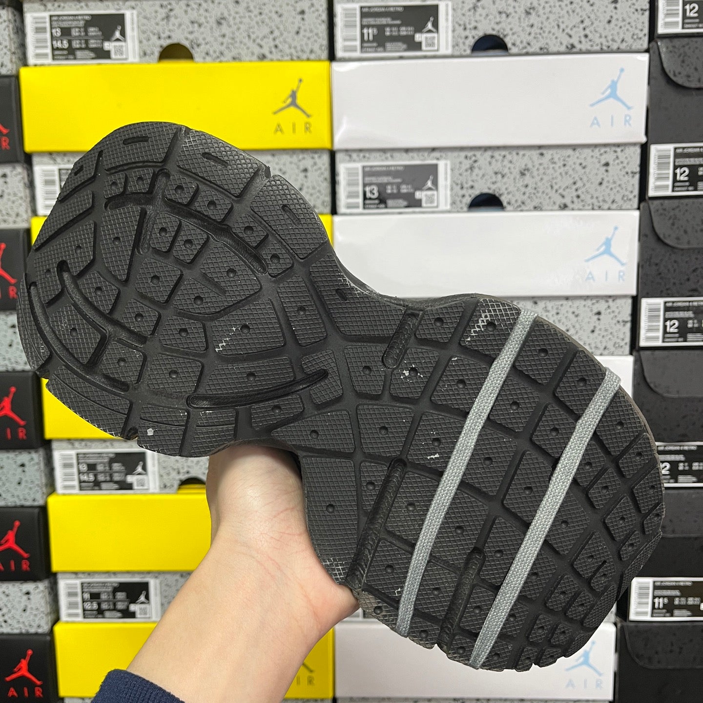 Unisex gray sneaker outsole view with tread pattern and lace strap detail