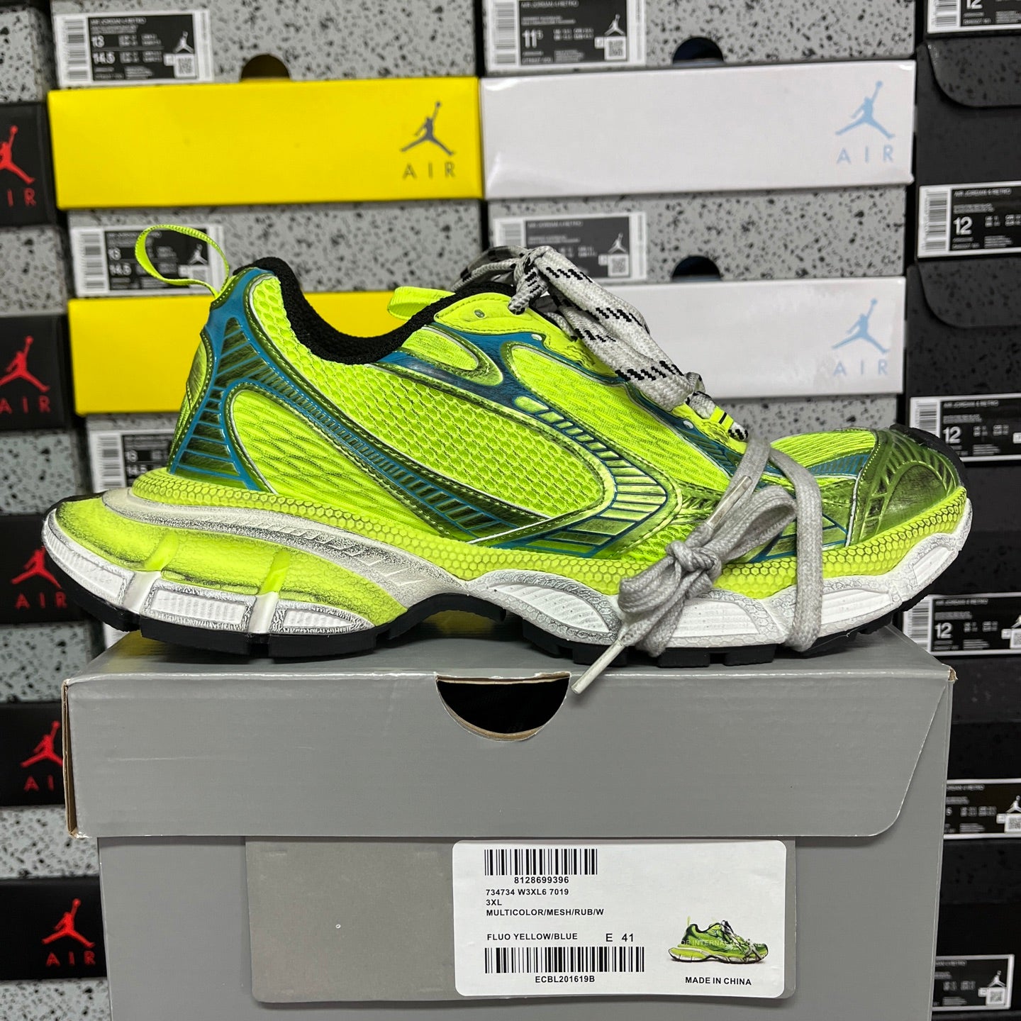 Neon green and blue lace-up running shoe on gray box, with chunky white midsole