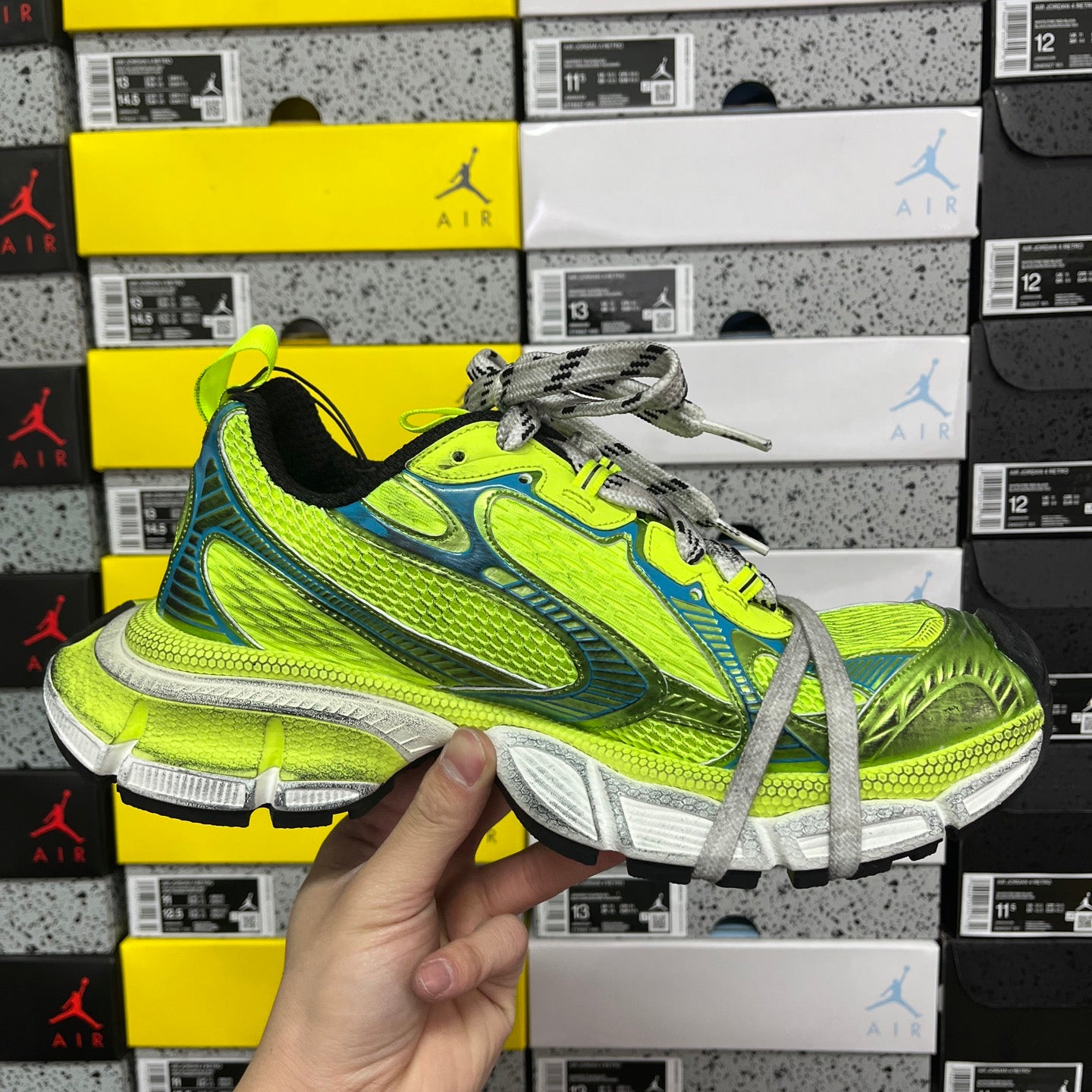 Front view of neon green and blue lace-up running shoe held in hand