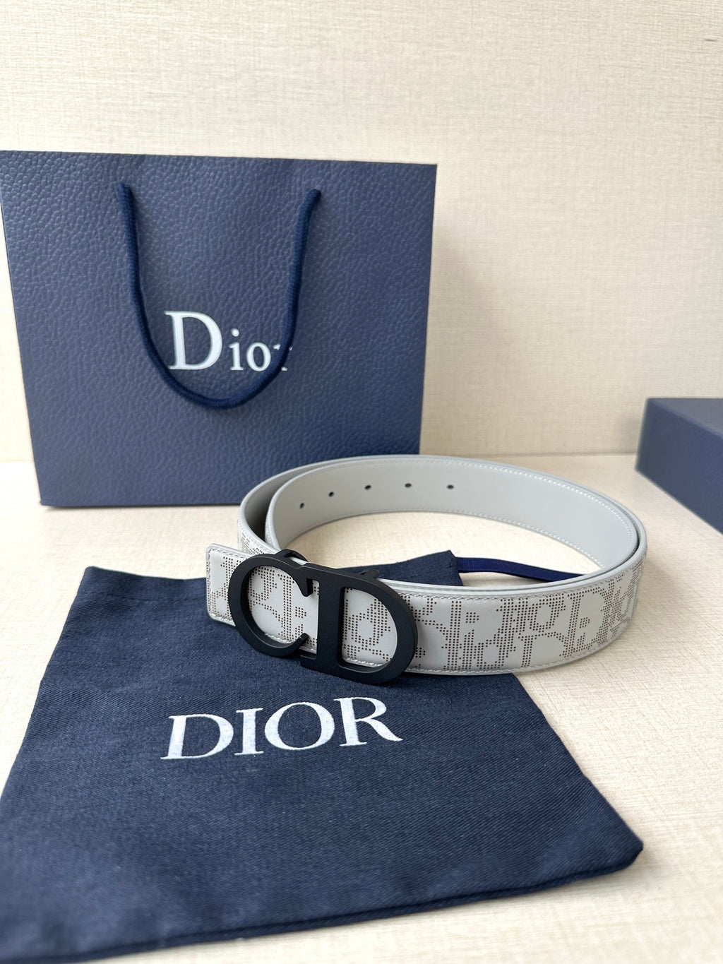 Dior belt with light gray logo strap, black CD buckle, perforated holes.