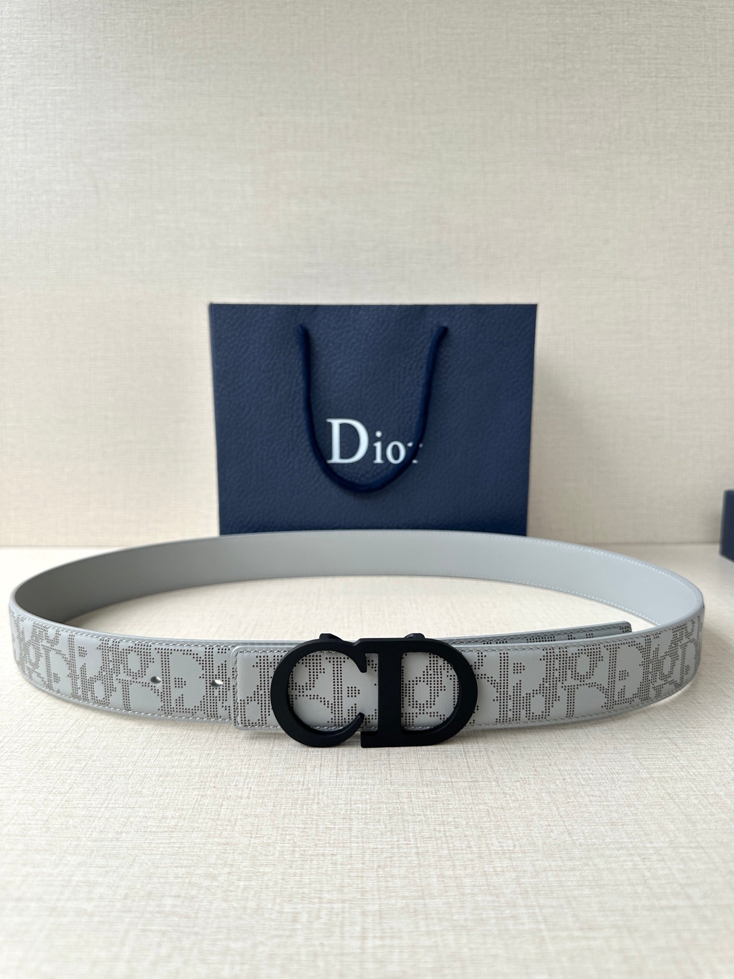 Dior belt with light gray/white logo strap and black CD buckle.