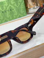 Tortoiseshell eyeglasses with rounded lenses and gold logo temple accent, close-up