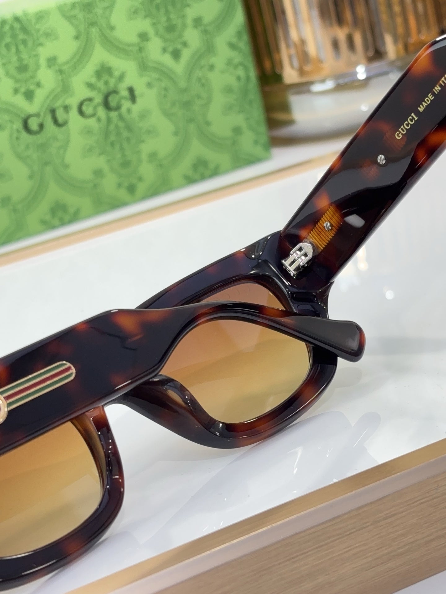 Tortoiseshell eyeglasses with rounded lenses and gold logo temple accent, close-up