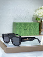 Black oversized sunglasses with dark lenses and gold logo bridge detail
