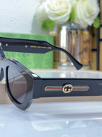 Dark blue eyeglasses with rounded frames and gold logo stripe at the temple, close-up