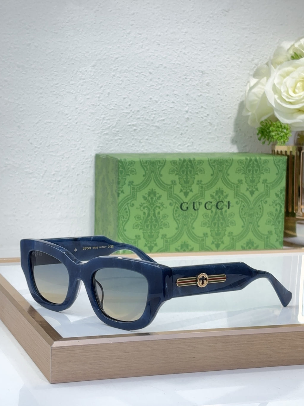 Navy blue oversized sunglasses with dark lenses and gold logo bridge detail