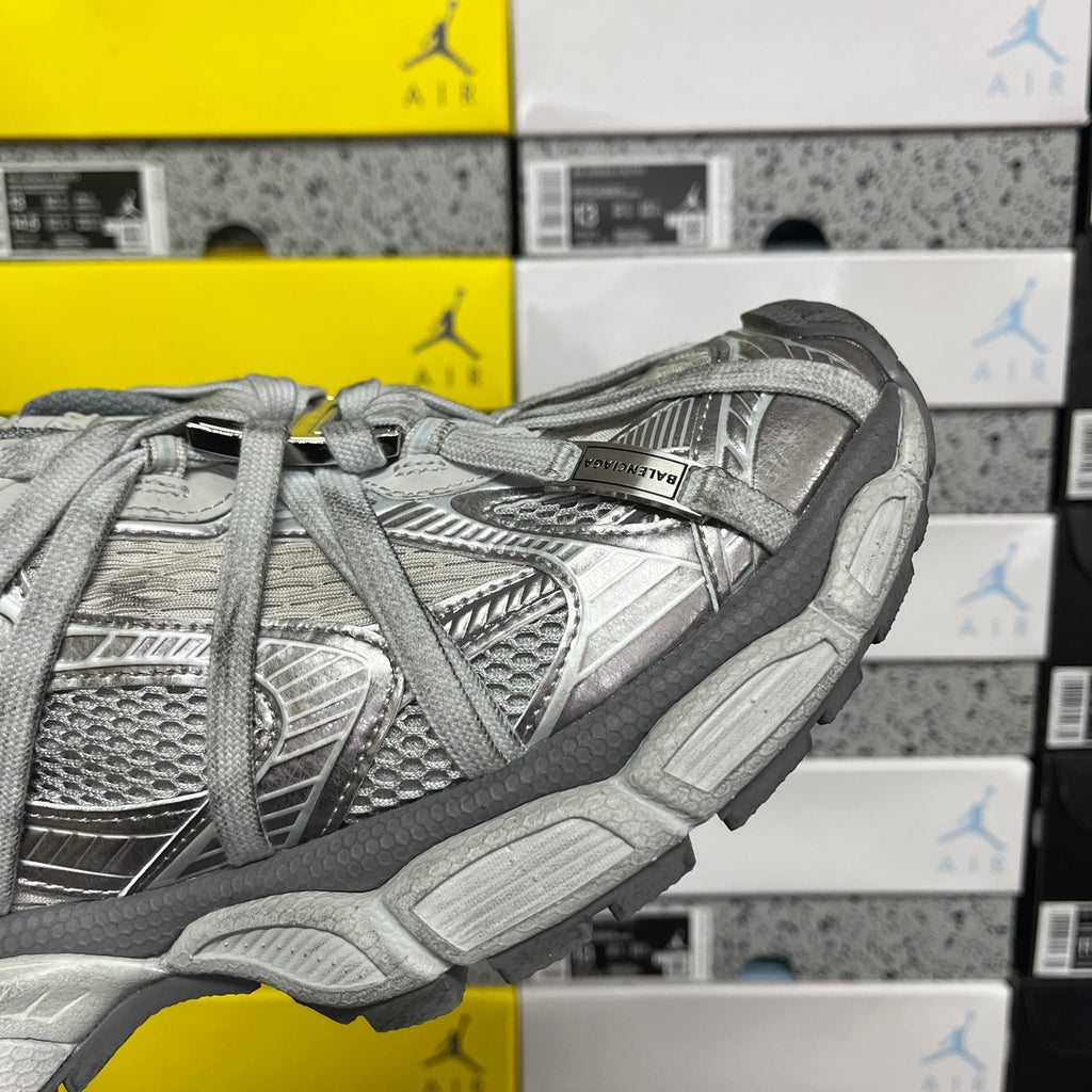 Gray lace-up sneaker with metallic logo patch on side and chunky midsole