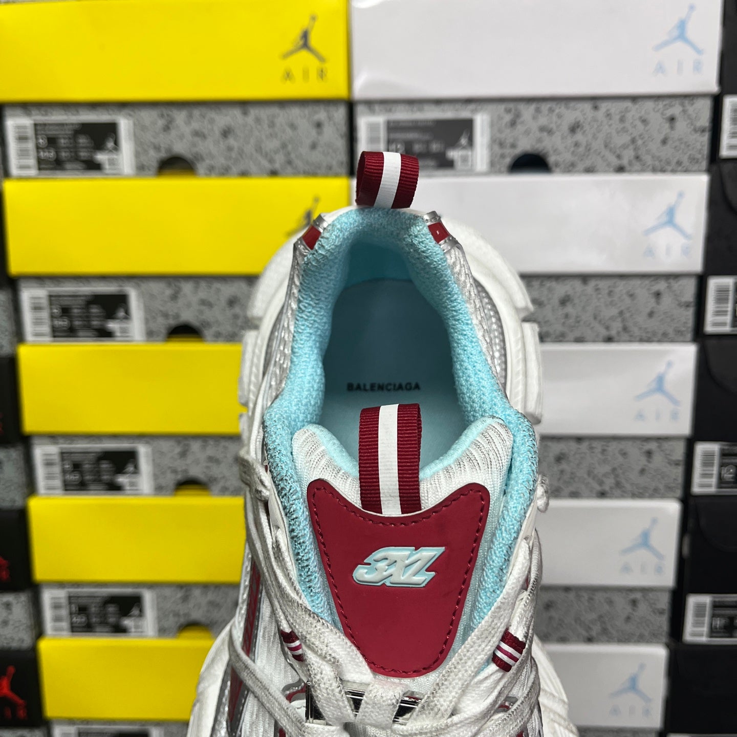Heel view of white sneaker with red tab and light blue inner lining