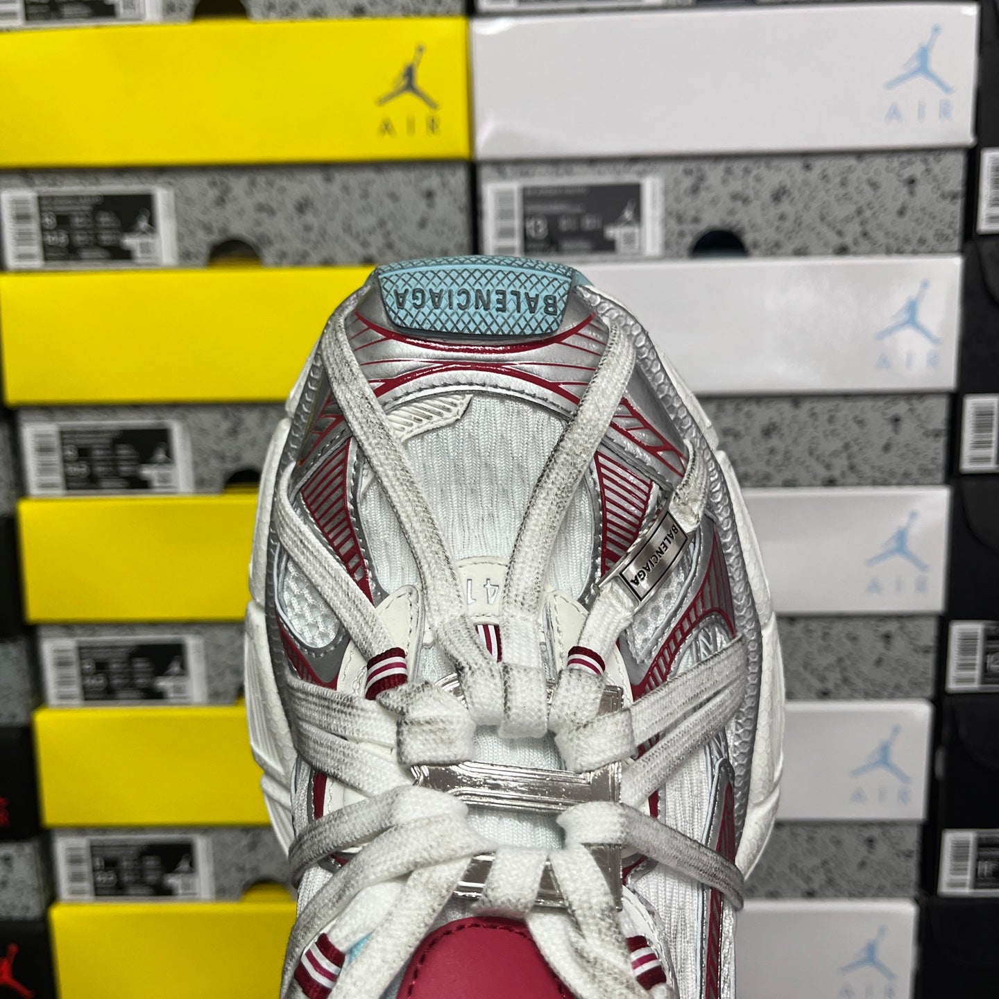 Back view of white lace-up sneaker with red panel stripes and light blue heel lining