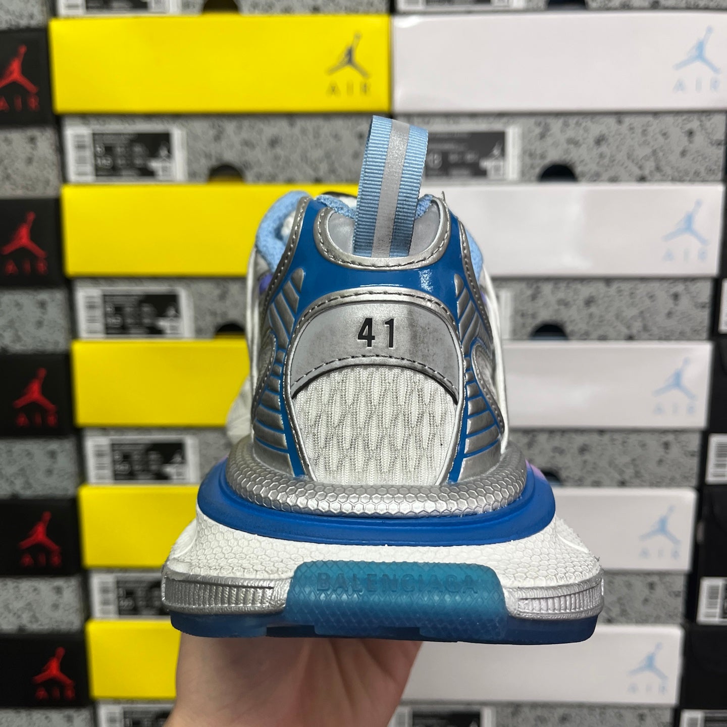 Heel view lace-up sneaker with blue back strap, gray outsole, and textured heel panel
