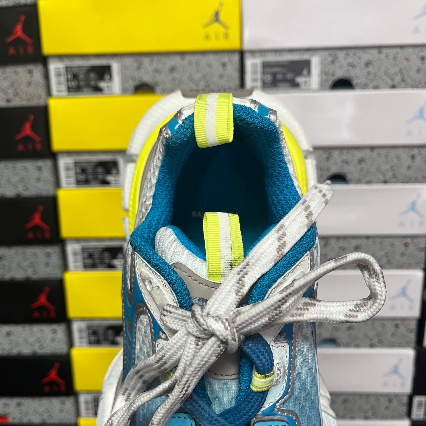 Unisex sneaker heel with blue lining, neon yellow tabs, and gray lace loops