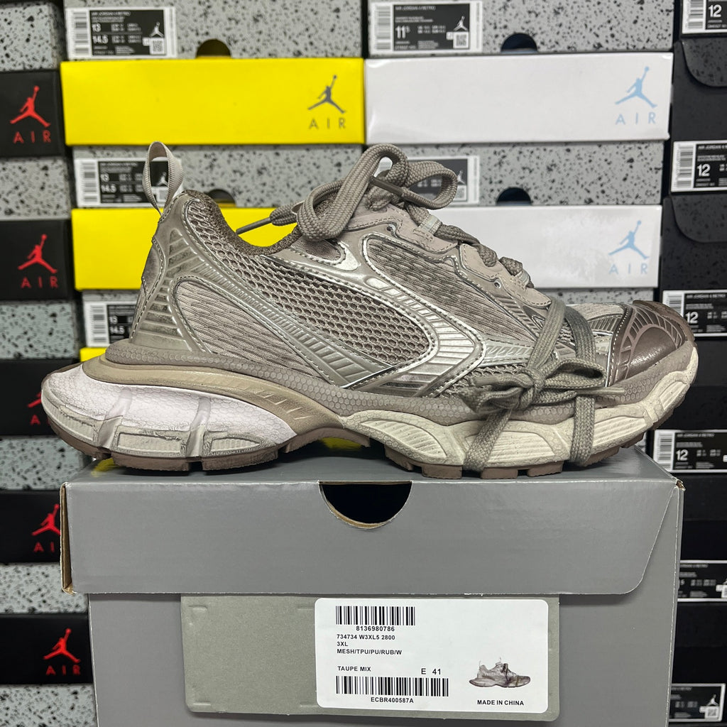 Gray lace-up athletic shoe with textured panels, stitched overlays, and thick rubber outsole