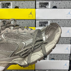 Gray lace-up sneaker side view with perforated-looking paneling and thick midsole