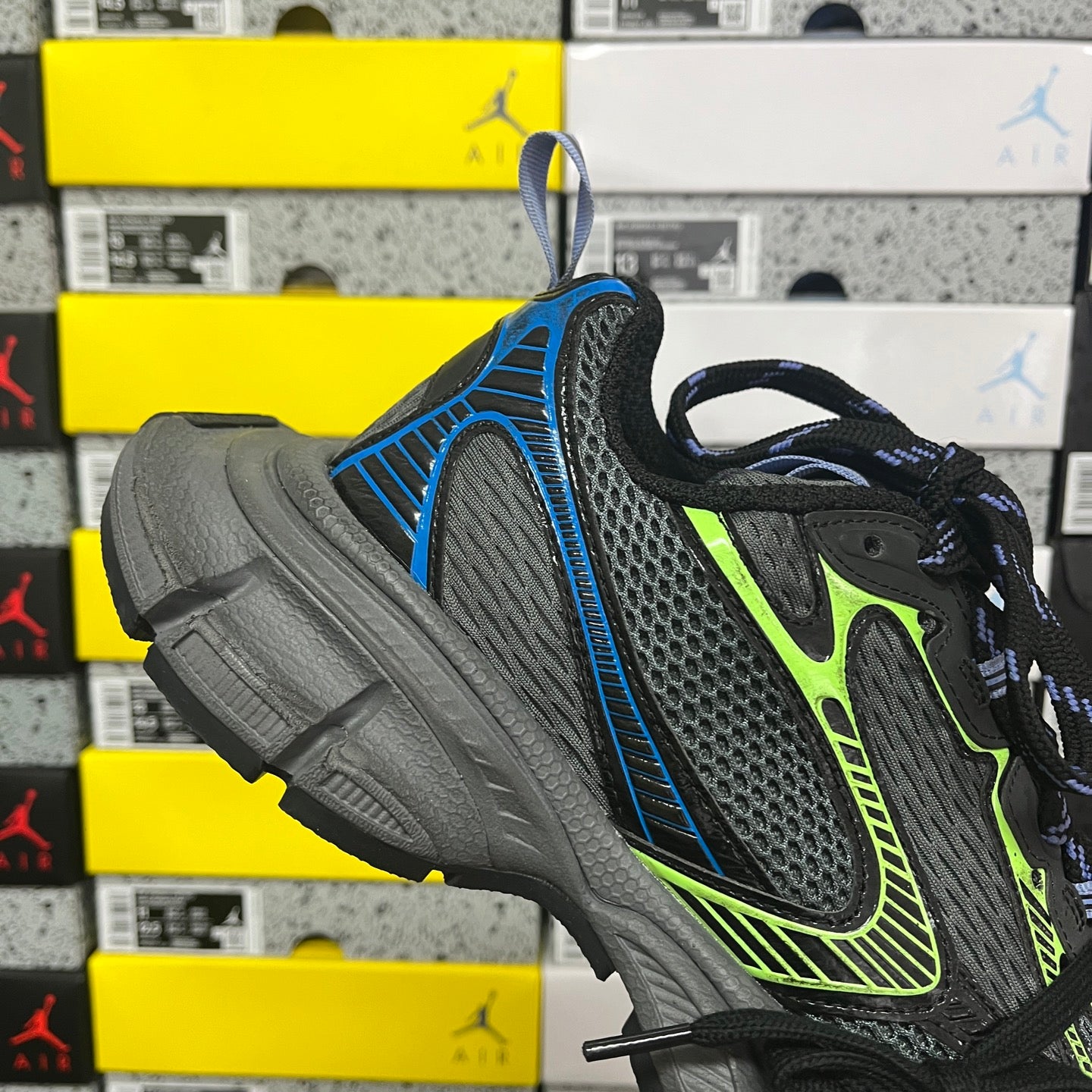 Balenciaga running sneaker with black mesh upper, neon green accents, and blue heel tab