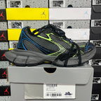 Black Balenciaga sneakers with mesh panels, neon green lines, and blue edging