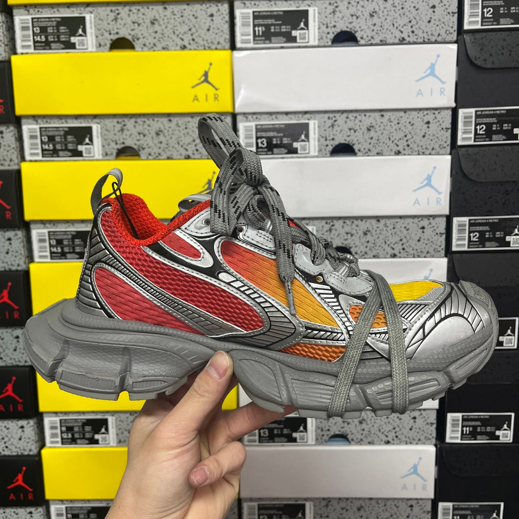 Three-quarter view of chunky sneakers in gray with red, orange, and white details