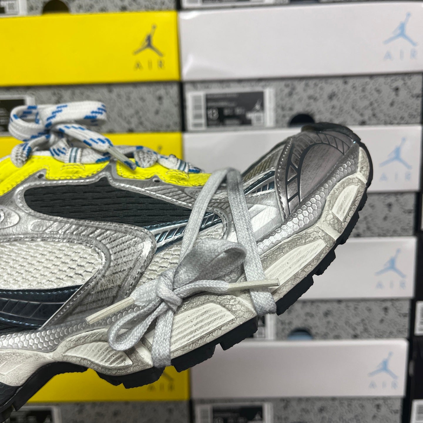 Grey and black running sneaker with neon yellow eyelet and white laces, side/back view