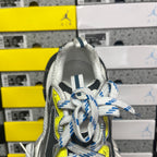 Grey sneaker with blue striped laces and neon yellow eyelet, tongue and collar close-up