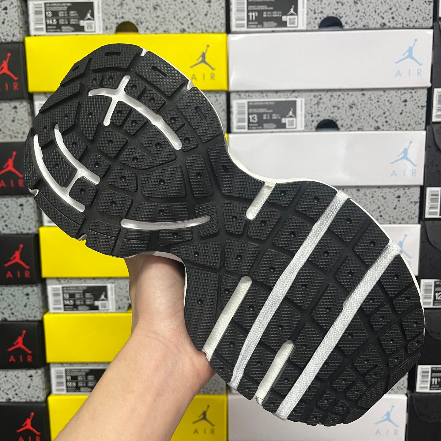 Unisex running shoe outsole view, black tread with white stripe pattern