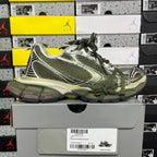 Green and silver sport sneakers on a box, side view with lace-up design