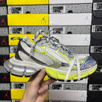 Silver and lime green athletic sneaker with white laces and blue heel, front angled view.