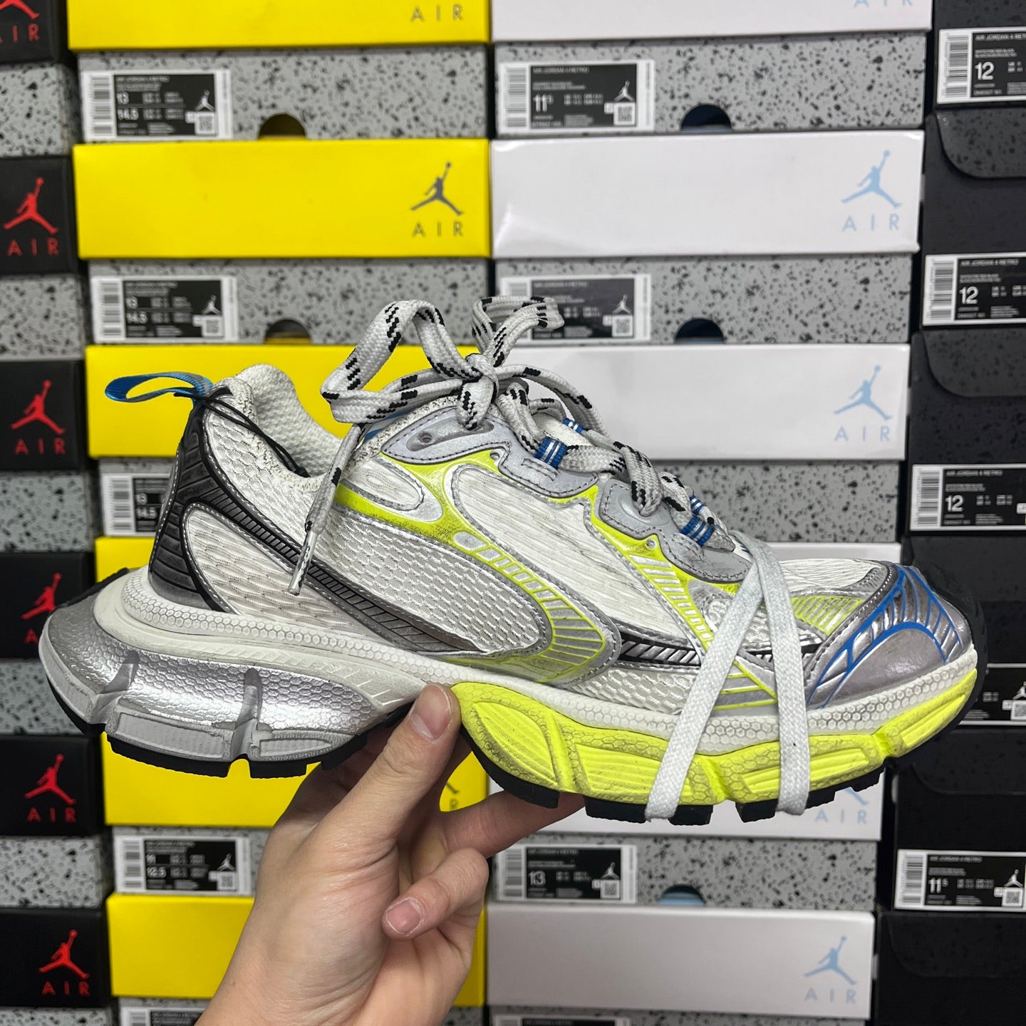 Silver and lime green athletic sneaker with white laces and blue heel, front angled view.