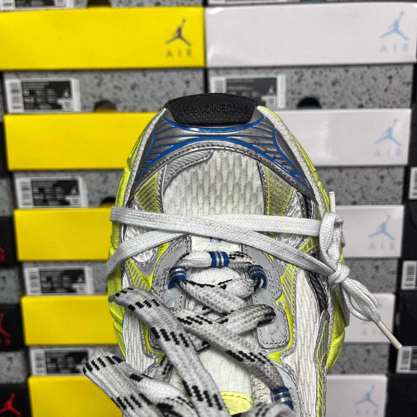 Silver athletic sneaker with mesh upper, white laces, neon lime and blue trim, close-up.