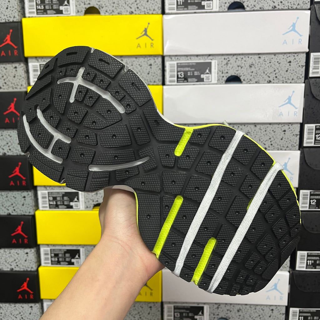 Black rubber outsole with gray tread and lime green edge, sneaker bottom view.