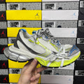 Silver and lime green athletic sneaker with white laces and blue accents, side view.