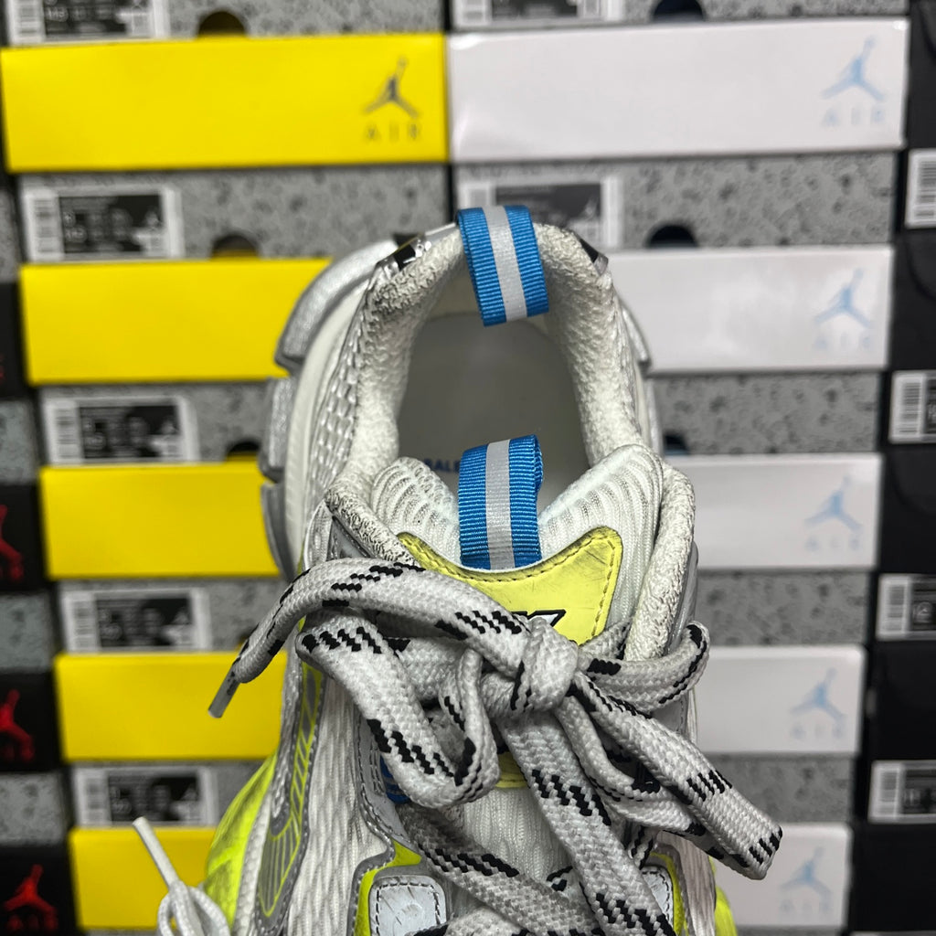 Silver sneaker collar with white laces, blue striped pull tab, neon lime logo detail.