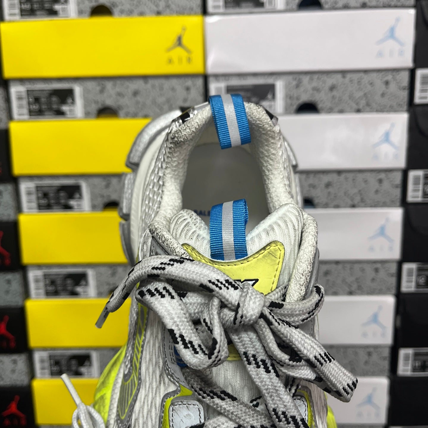Silver sneaker collar with white laces, blue striped pull tab, neon lime logo detail.
