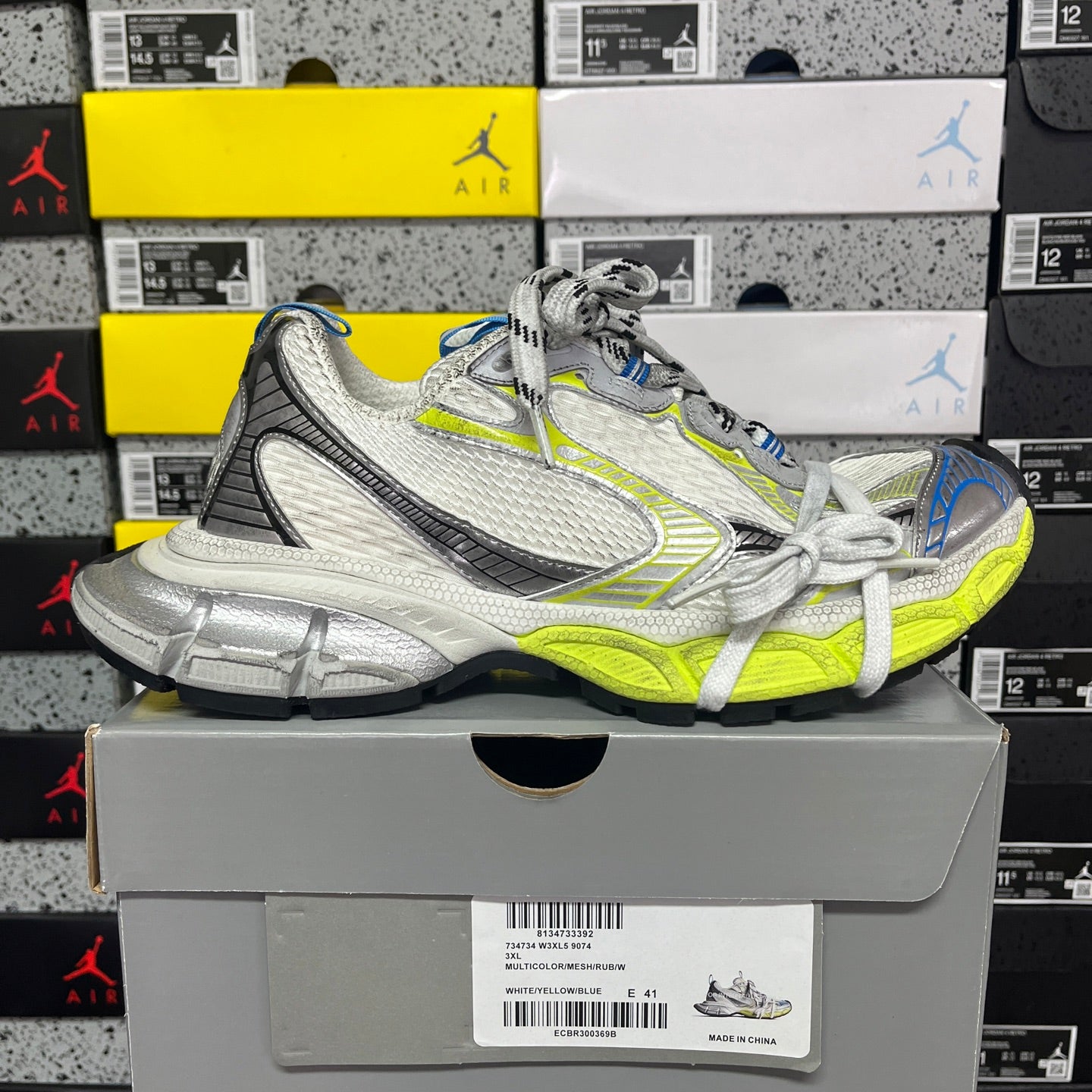 Silver and lime green athletic sneaker with white laces, resting on a box, angled side.