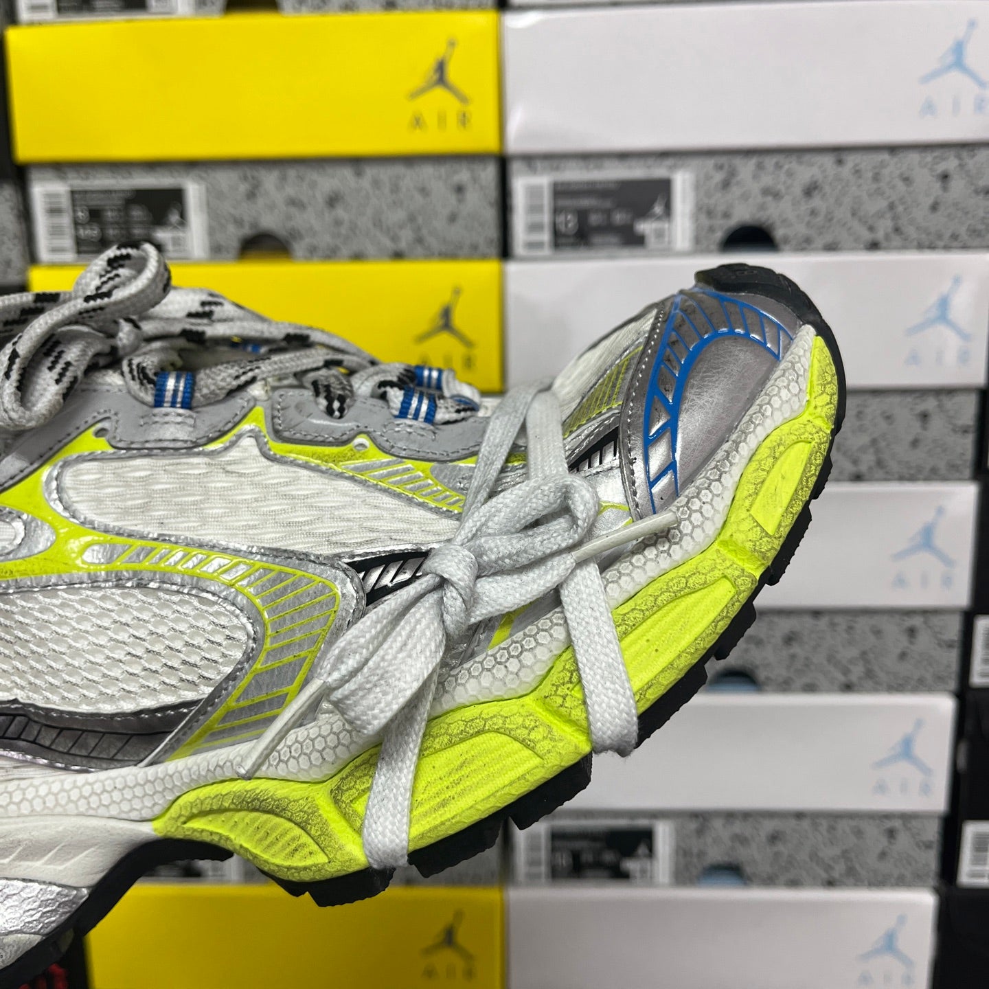 Silver and lime green athletic sneaker heel and toe with white laces and blue side panel.