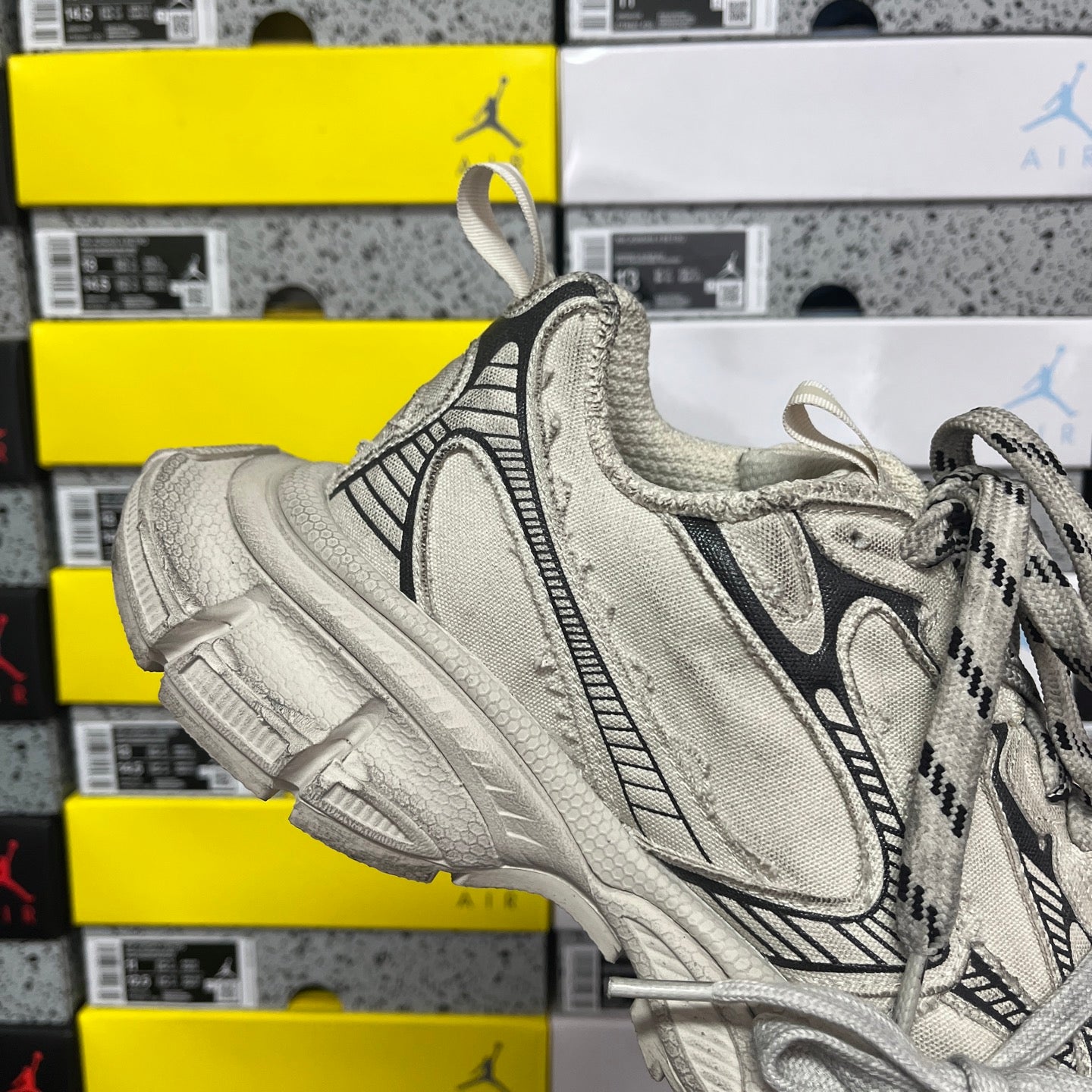 Light gray sneaker with lace-up closure, textured heel pull tab, and chunky sole