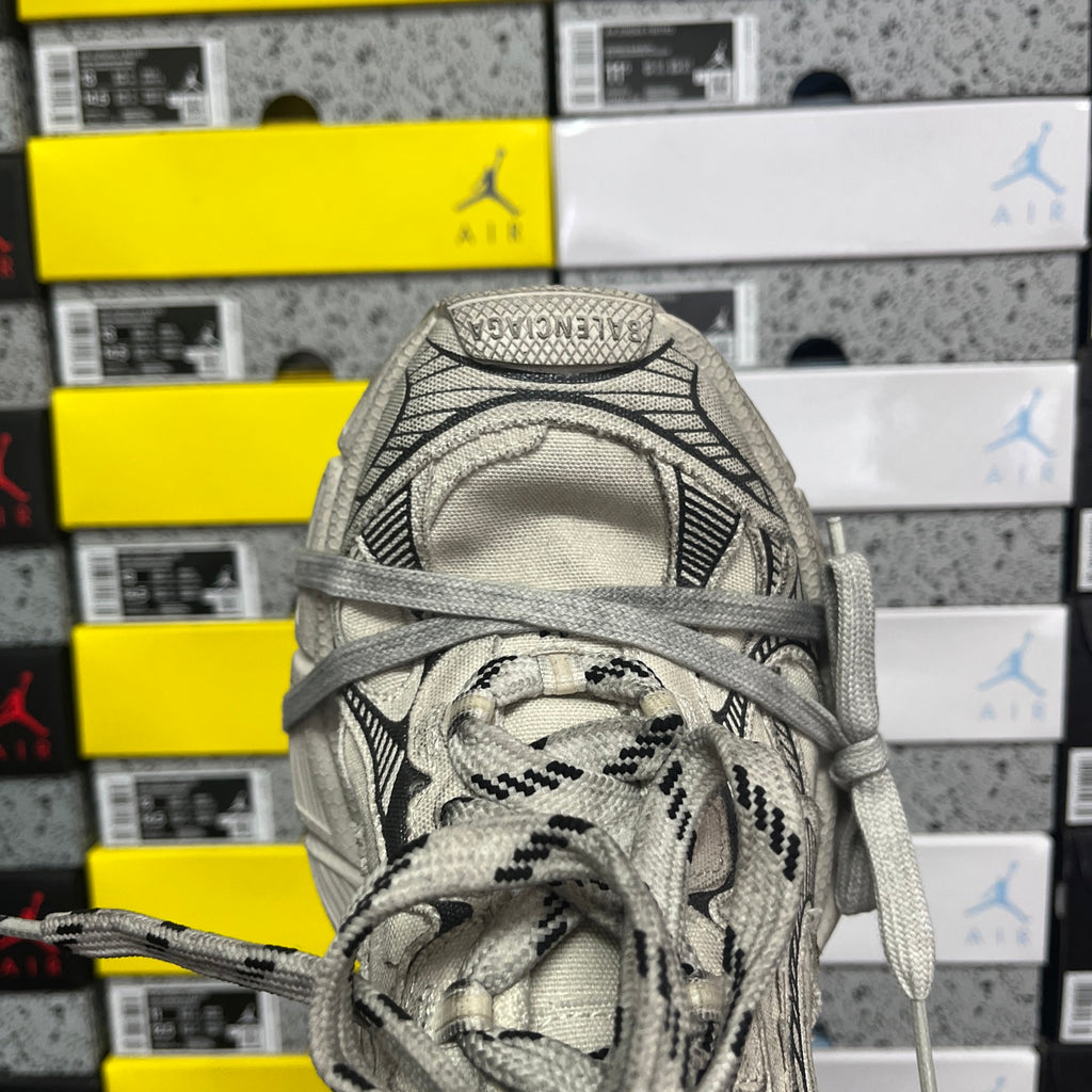 Light gray sneaker upper with mesh-like panels and lace cords, rear close-up