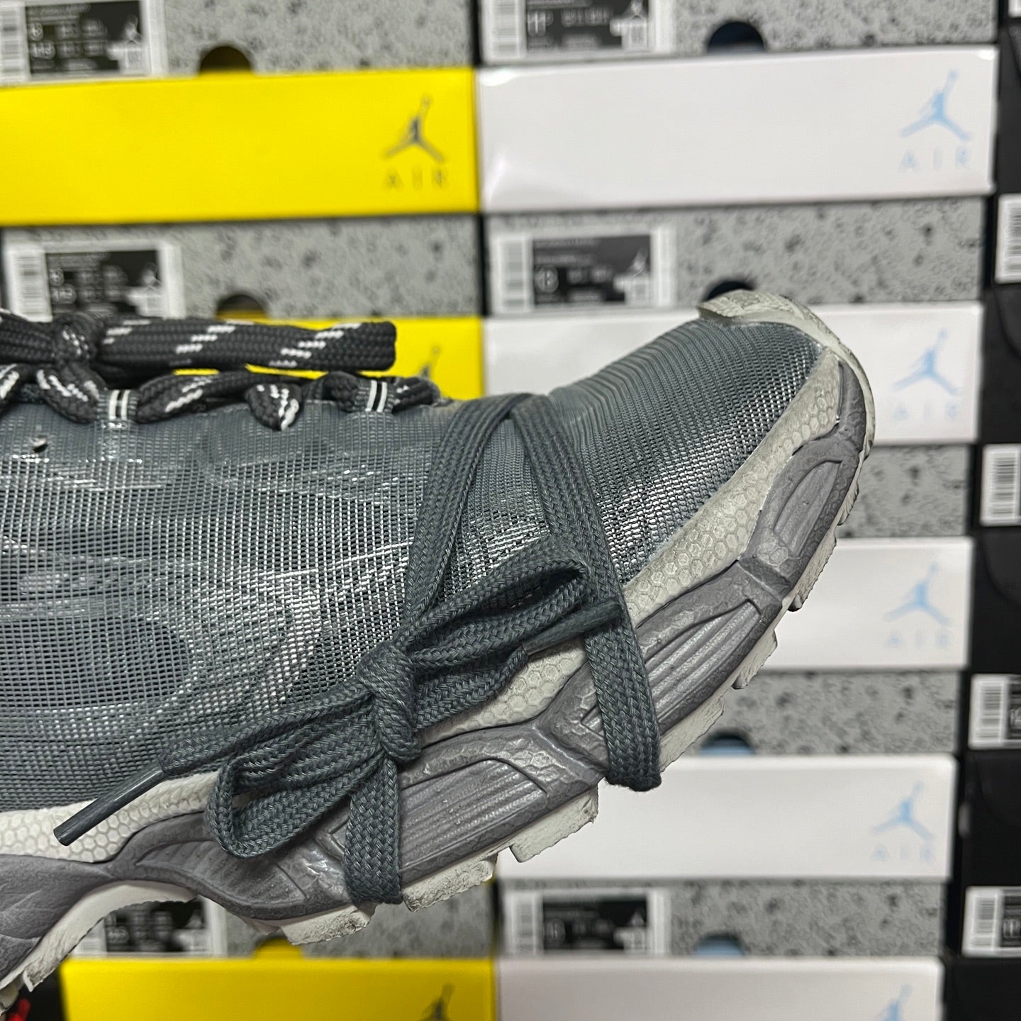 Gray athletic sneaker with laced upper, textured fabric, and chunky sole