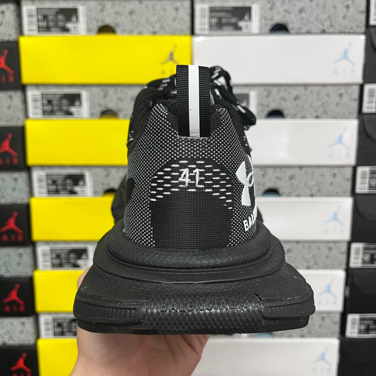 Black knit sneaker heel with side strap and cushioned collar, rubber sole edge visible