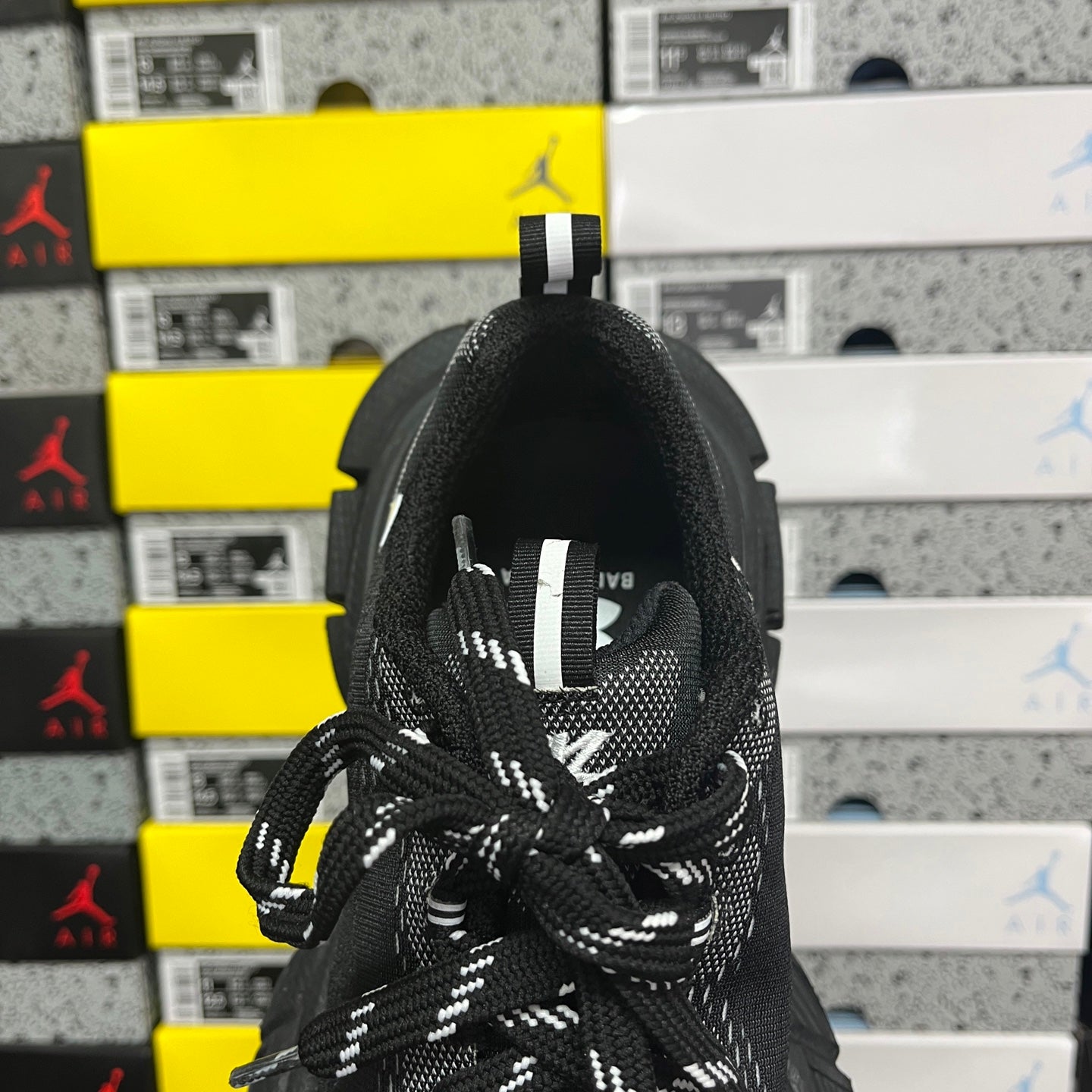 Black sneaker heel and lace area with fabric pull tab and stitched logo detail