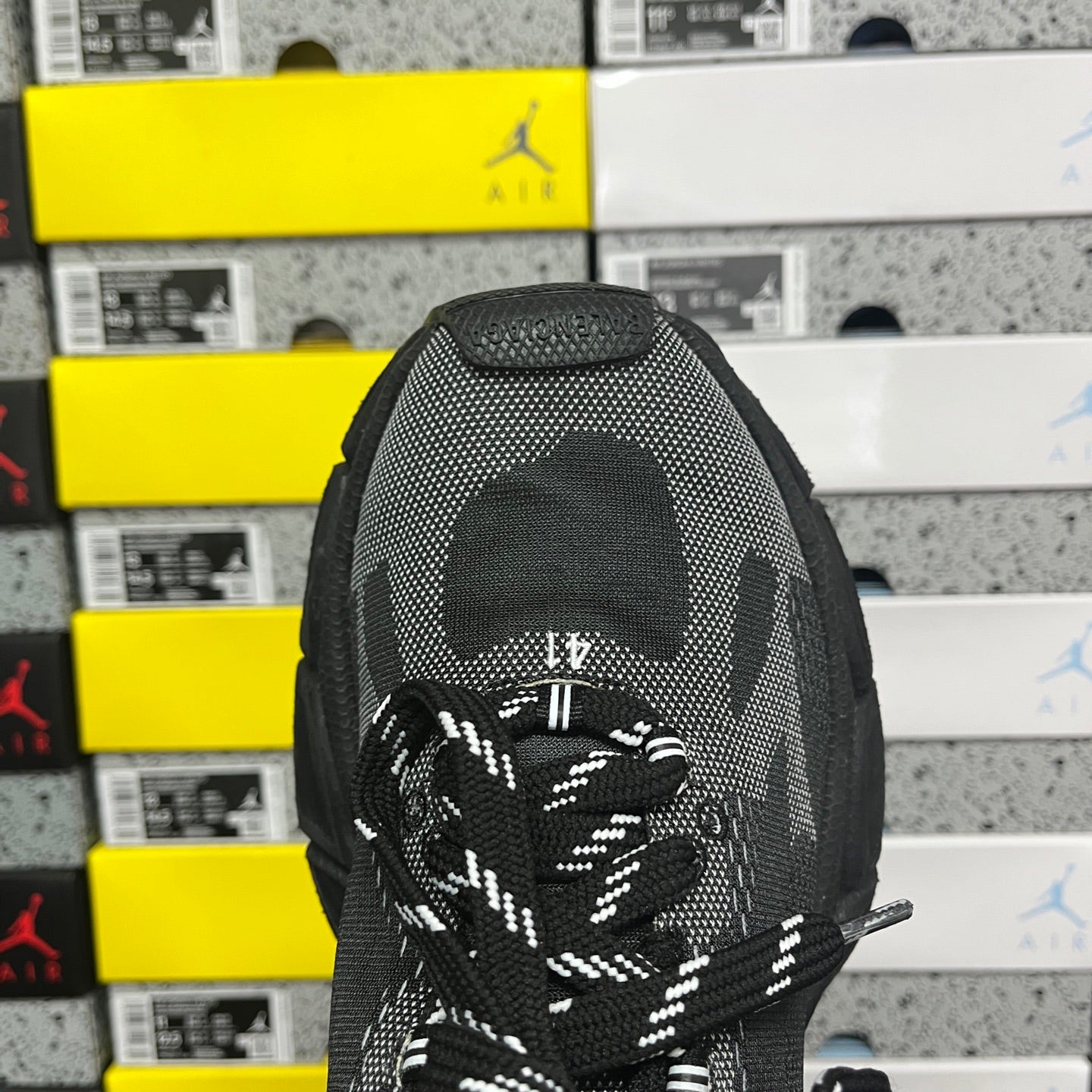 Black knit sneaker tongue with circular Under Armour logo and Balenciaga lace area