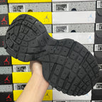Black outsole of lace-up sneaker with grid tread pattern and raised traction lugs