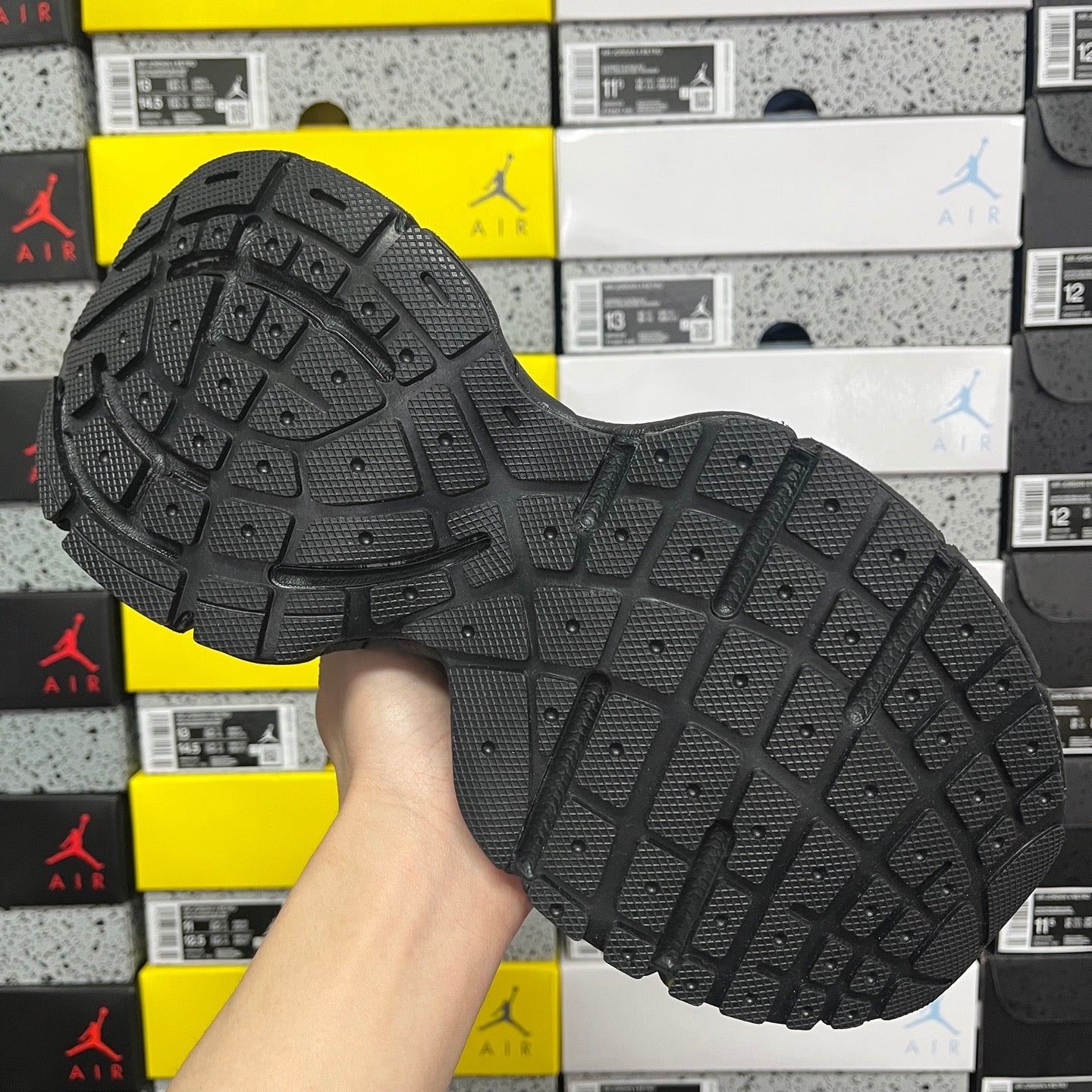 Black outsole of lace-up sneaker with grid tread pattern and raised traction lugs