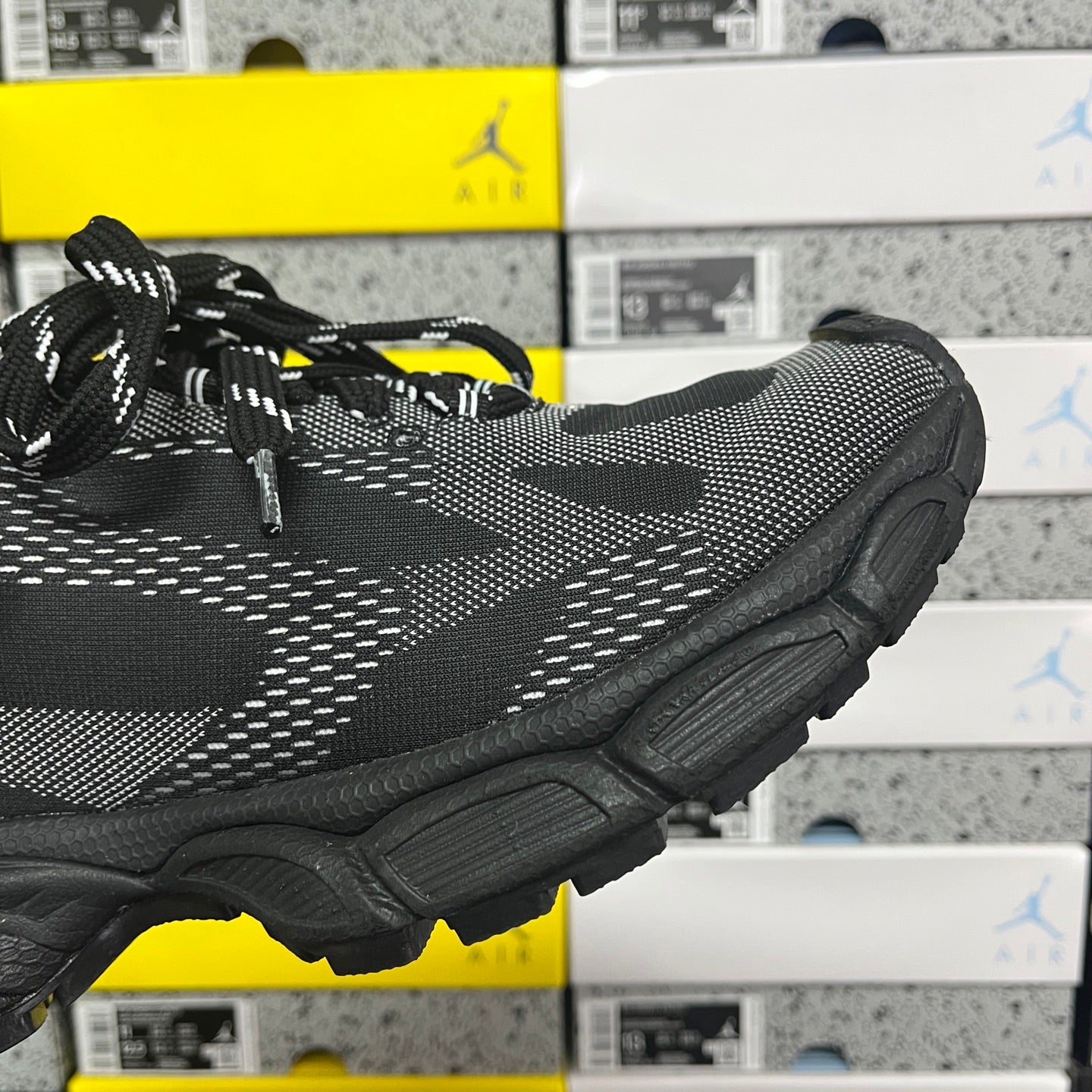 Black lace-up knit sneaker showing side profile and thick treaded rubber sole