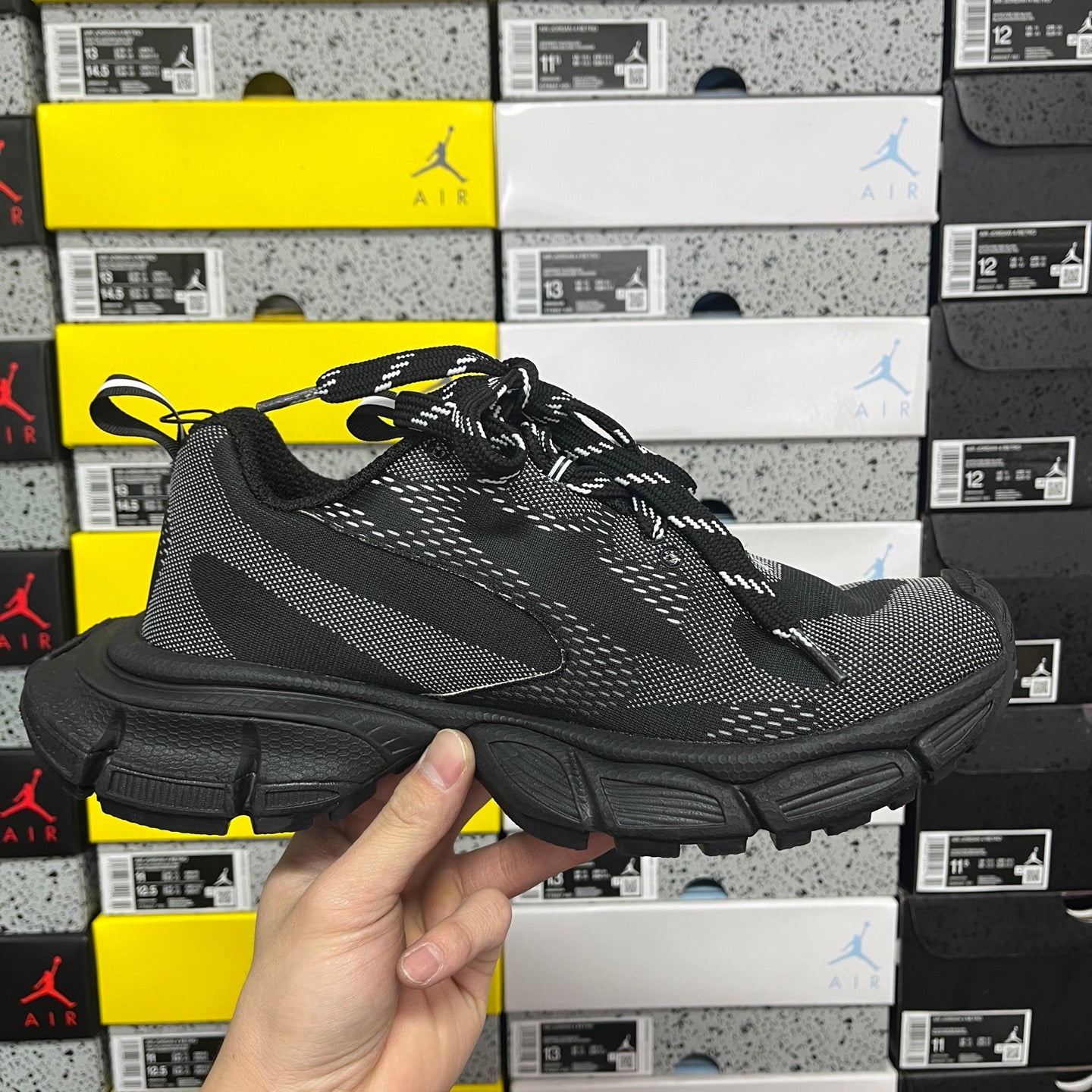 Black lace-up knit sneaker front-quarter view with chunky rubber sole and side logo