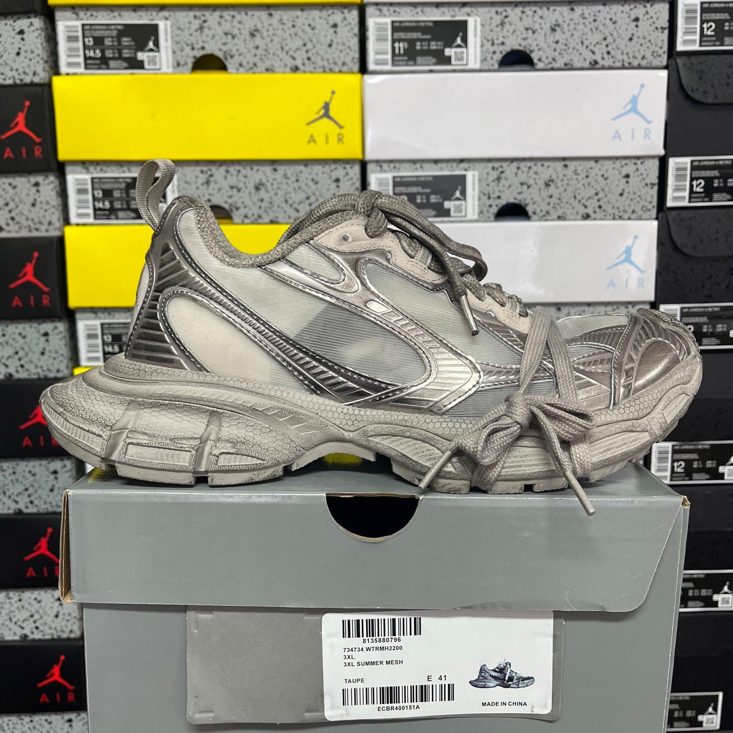 Balenciaga unisex gray lace-up sneaker resting on shoebox label side view.