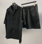 Black elastic-waistband shorts next to a black button-up shirt