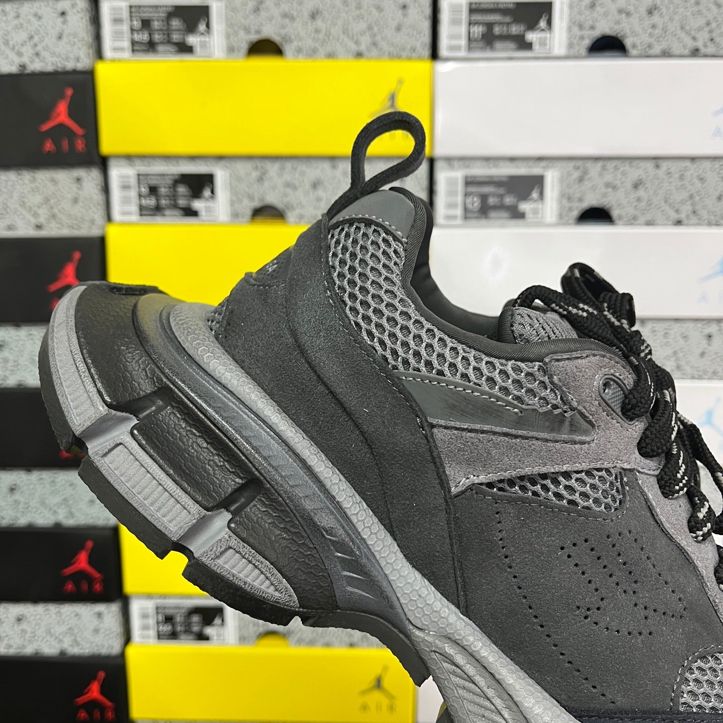 Grey sport sneaker with mesh side panels, black laces, and rugged tread